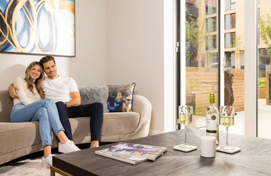 Couple sitting on the sofa of their Galliard Homes apartment