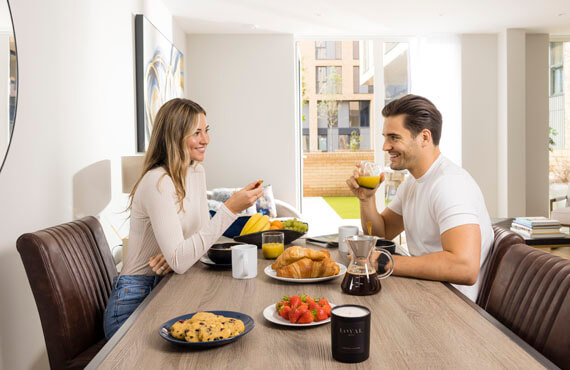Couple enjoying enjoying breakfast in their new Help to Buy apartment by Galliard Homes