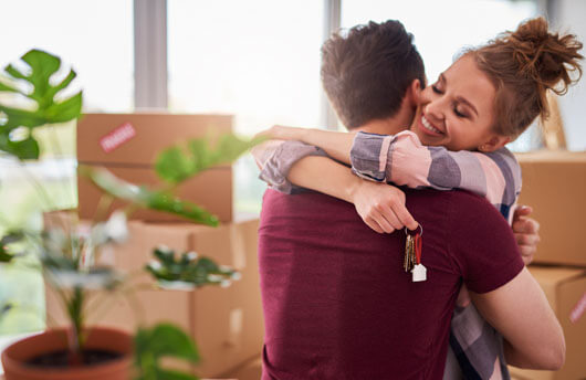First-time buyers embracing after picking up the keys to their new build apartment