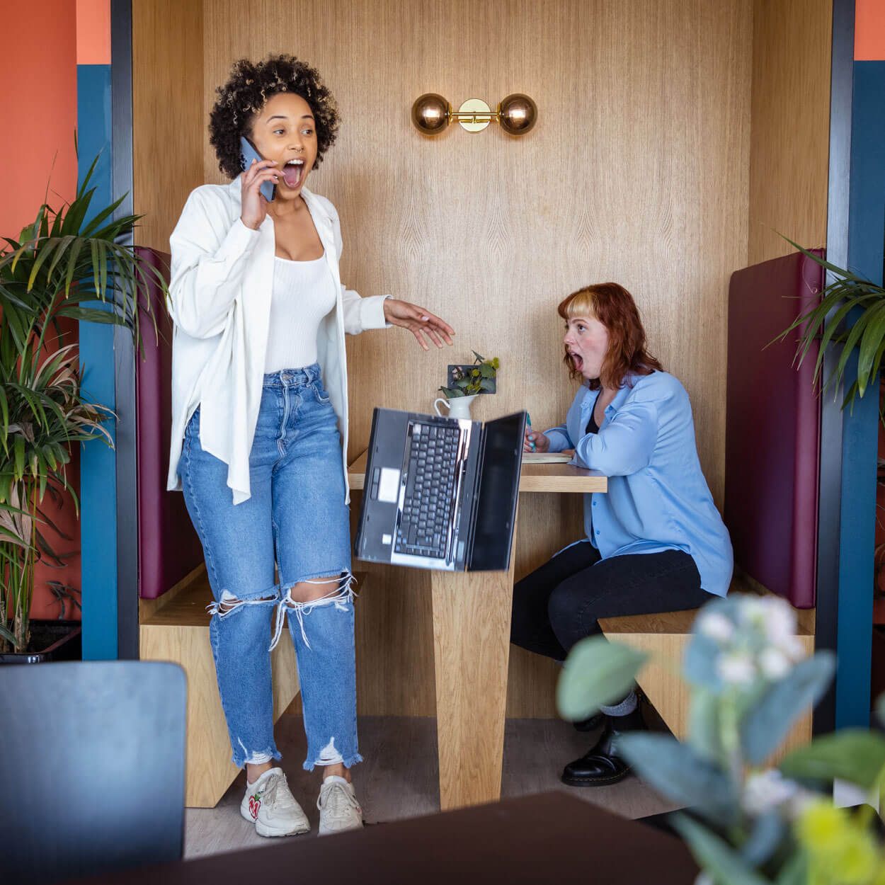 Person on the phone who knocks her laptop off the desk in shock