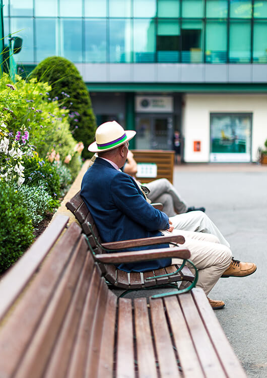 A Wimbledon Tennis spectator sitting on a bench.