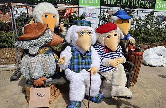 The Wombles sitting on a bespoke Wombles bench outside Galliard's development, Wimbledon Grounds.