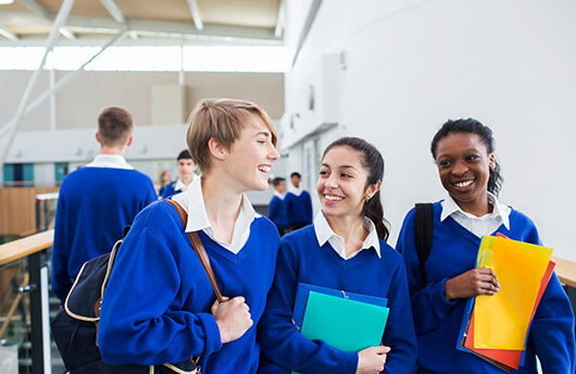 School children smiling in a corridor.