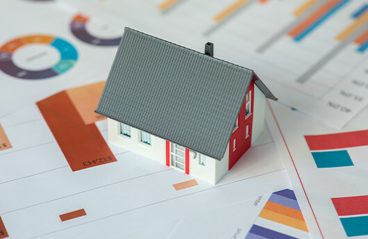 A model house sitting on top of paperwork.