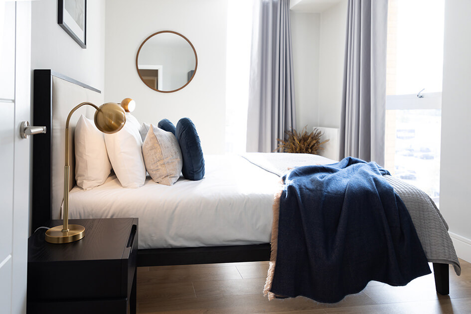 A bed and mirror in a Wimbledon Grounds show apartment.