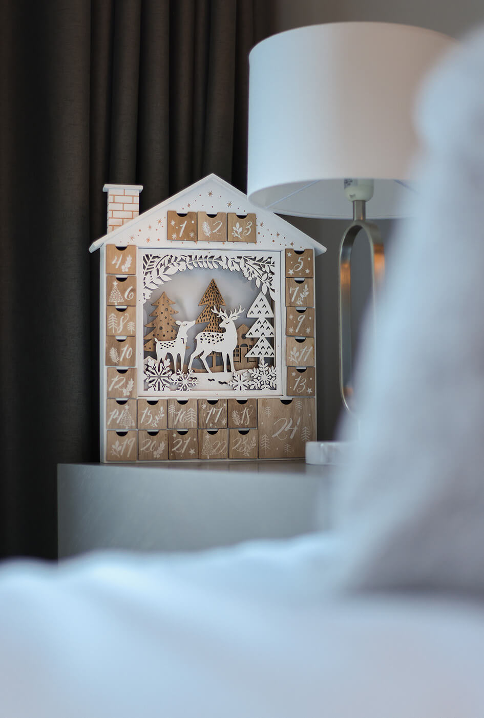 A close-up of a wooden advent calendar on a bedside table.