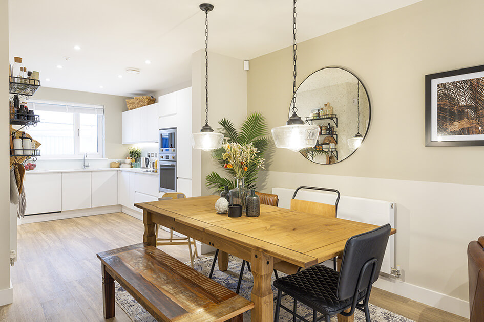 A kitchen and dining area complete with a U-shaped white kitchen and wooden dining table at Brooks Dye Works in Bristol.