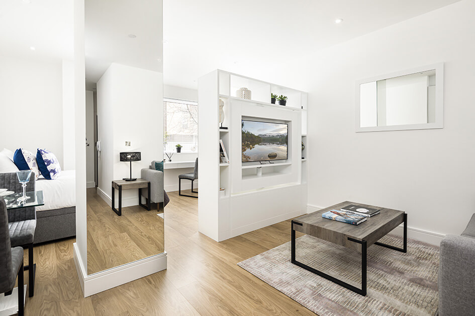 A living area at a studio apartment at Papermill House in Romford, complete with a white entertainment unit with a swivel TV.