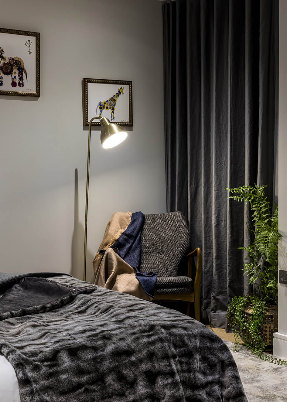 A chair and a bed in a cosy corner of a Wimbledon Grounds bedroom.