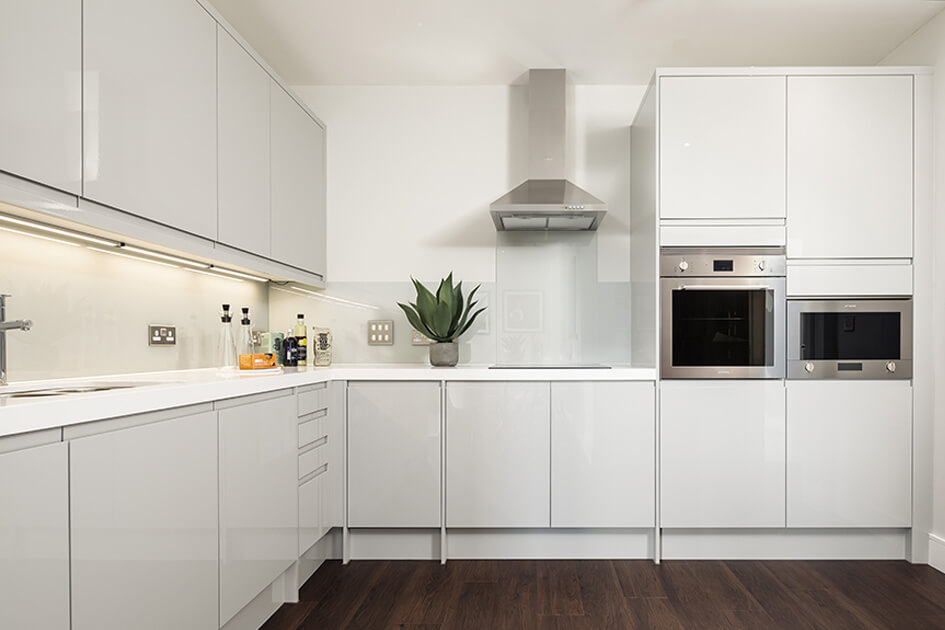 A white L-shaped kitchen in a show apartment at Orchard Wharf.