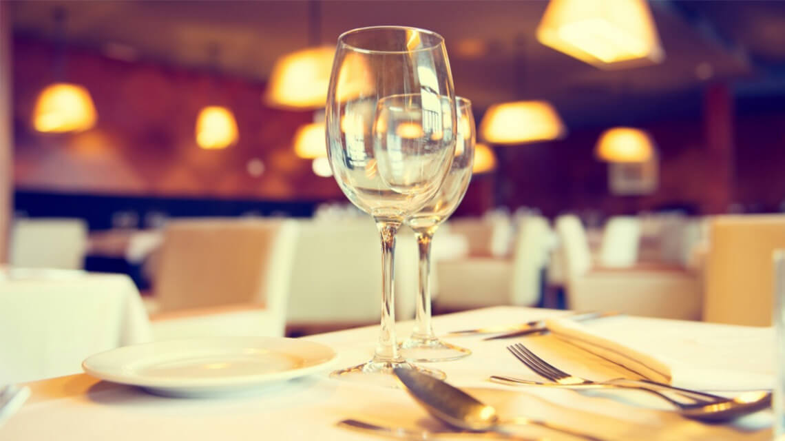 A dining table in a restaurant with plates, glasses and cutlery.