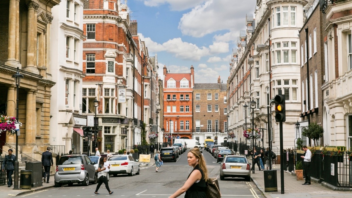 A woman crossing a road on a street in West London.