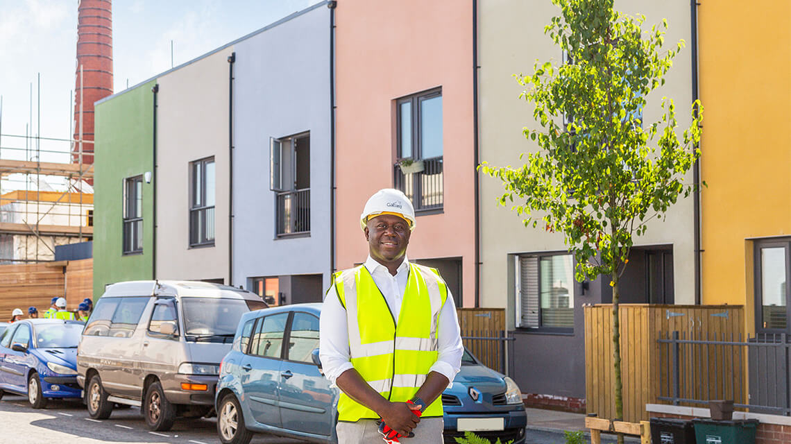 George Baffoe-Djan, Head of Strategic Partnerships at Galliard Homes standing outside houses at Brooks Dye Works.