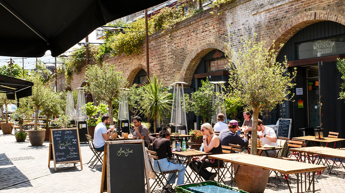 People sitting outside of restaurants and bars in Deptford.