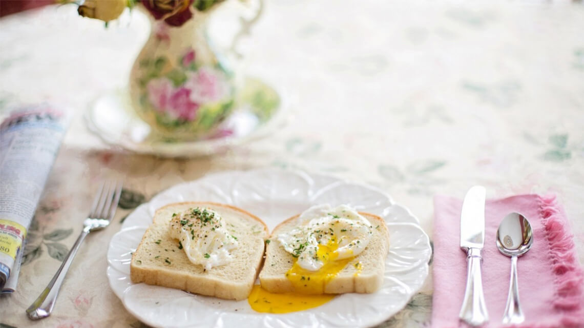 A dining table with poached eggs on toast.