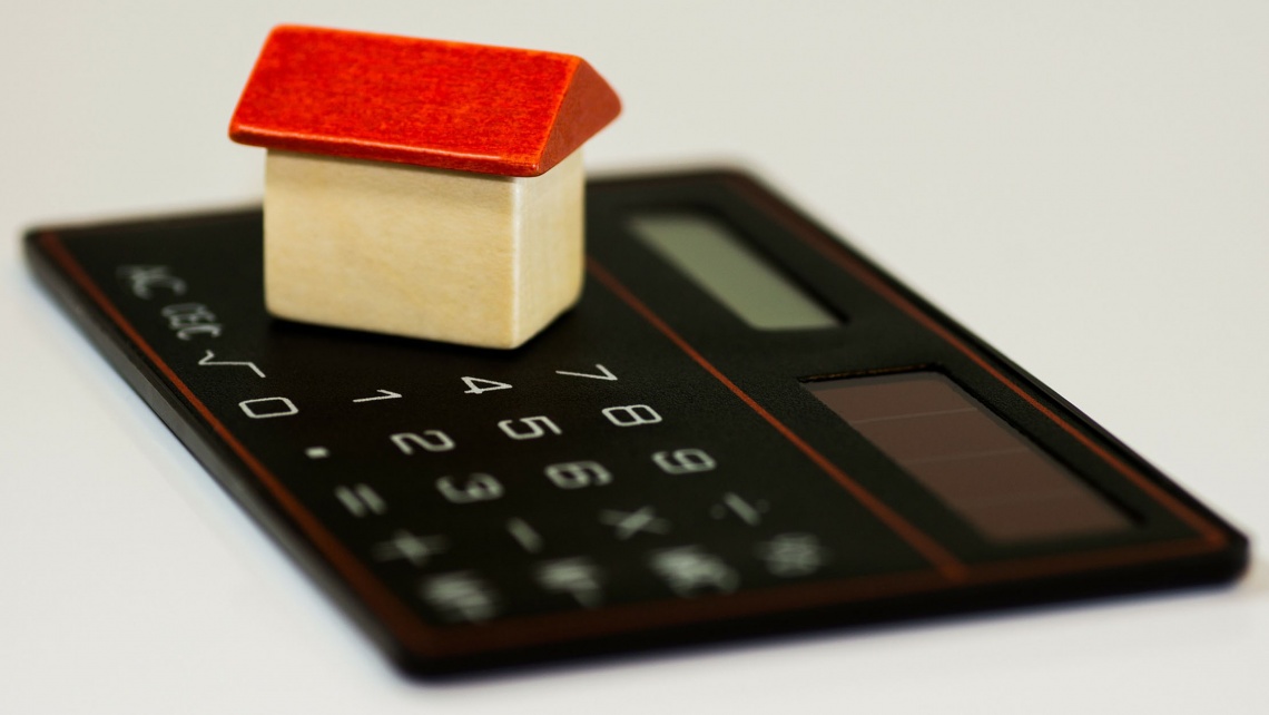 A mini wooden house on a calculator.