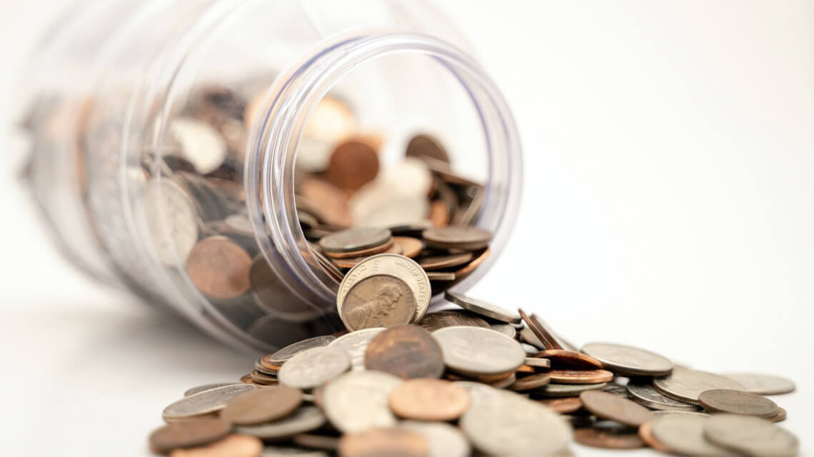 A jar of change over spilling, symbolizing saving for your first home.