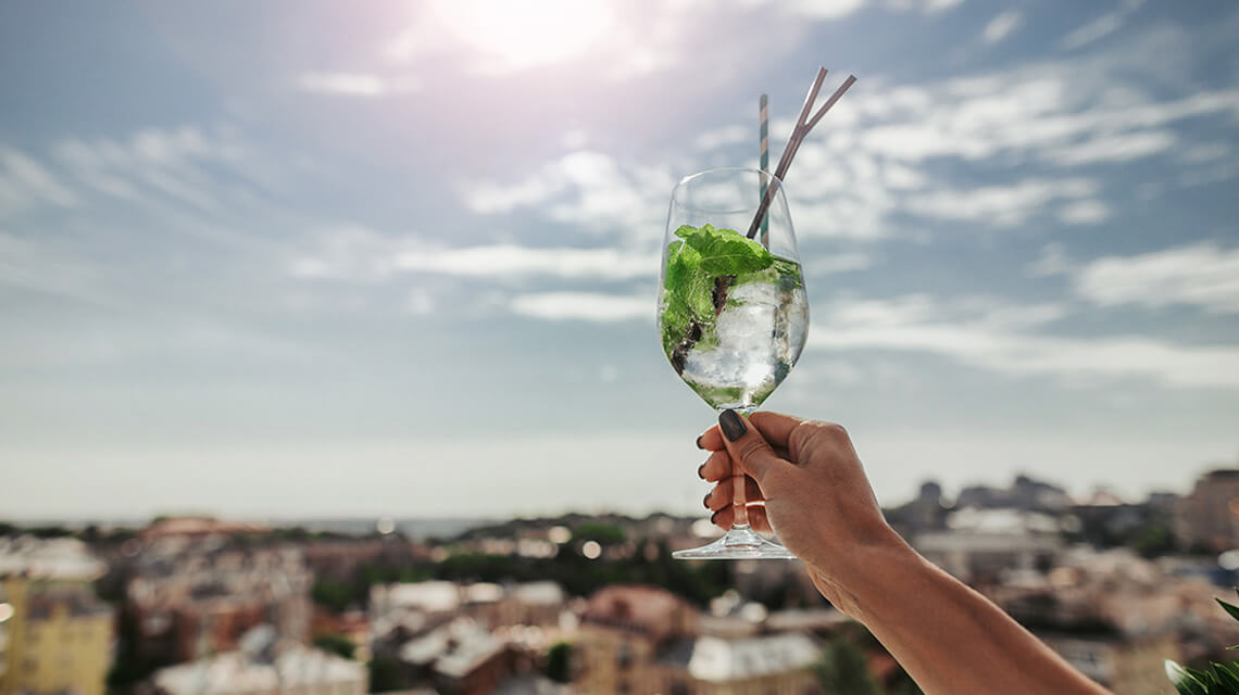 Woman holding a cocktail at a rooftop bar.