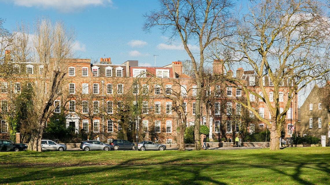 A row of houses across the street from a park in Clapham.