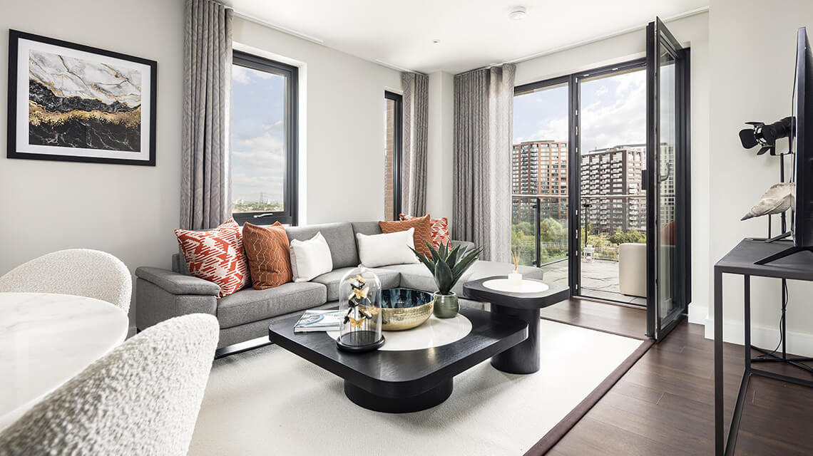 The living area of a show apartment at Orchard Wharf with balcony views of the River Lea.