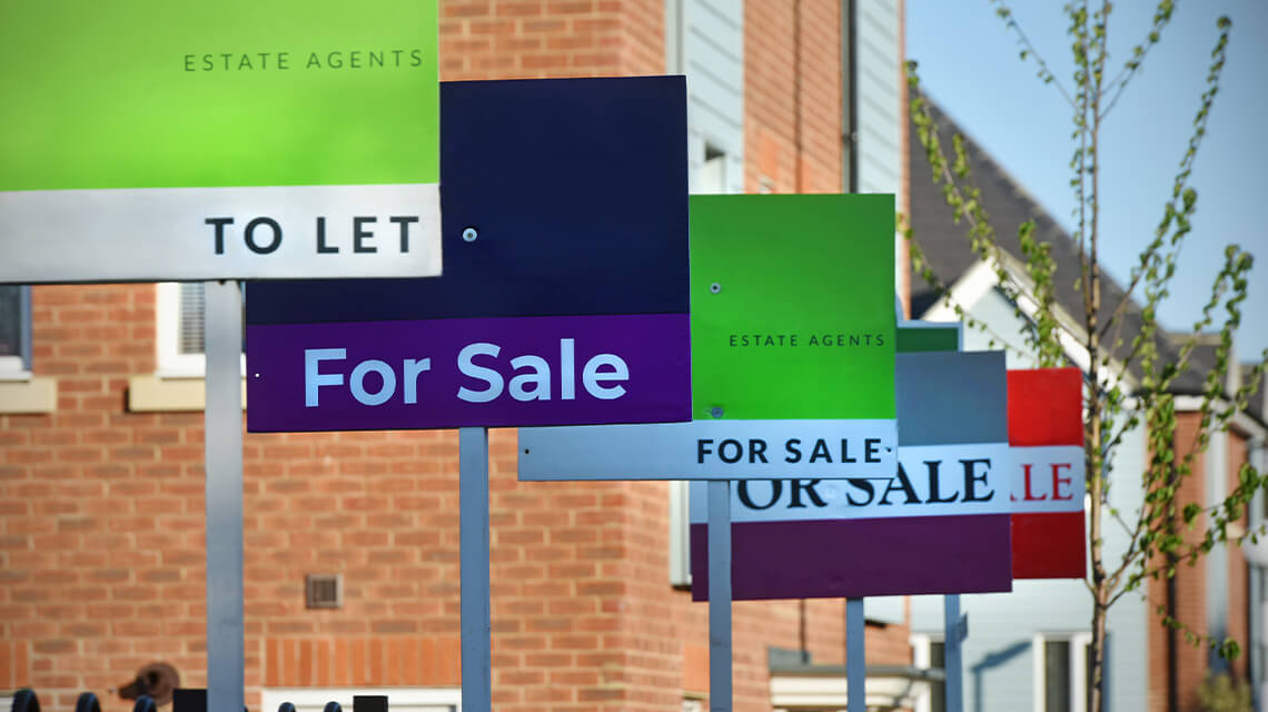 A line of estate agent boards on a street.