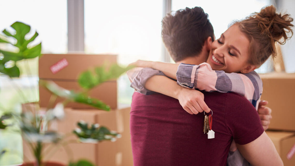 Couple hugging after getting the keys to their new home