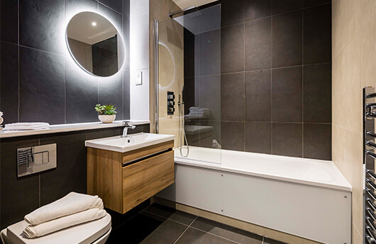 A CGI of a bathroom with black tiles at Newacre House by Galliard Homes.