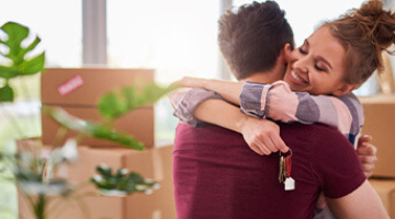 A couple hugging surrounded by boxes having just moved in