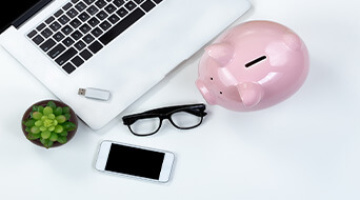 A piggy bank, phone, laptop and glasses.