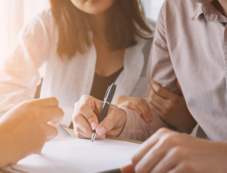 Overseas couple signing contacts for their new property purchase